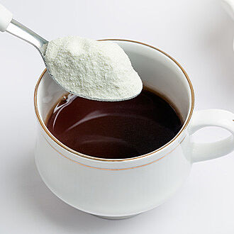Cup with coffee and spoon with dairy powder